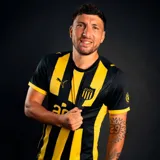 Camiseta de fútbol Puma del Club Atlético Peñarol, modelo Home. Diseño a rayas verticales amarillas y negras, con cuello redondo y detalles en amarillo en las mangas. Incluye logo de Puma y escudo del club en el frente.