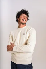 Buzo de cuello redondo en color beige claro, confeccionado en tejido de algodón. Presenta un diseño minimalista con el logo bordado de la marca en el pecho y puños acanalados.