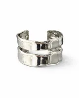 Pulsera tipo brazalete abierto, rígida y ancha, compuesta por dos bandas superpuestas con acabado plateado brillante y bordes irregulares.