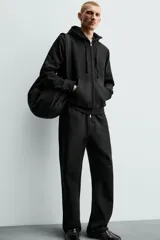 Pantalón jogger de corte regular fit y color negro, confeccionado en tejido compacto de algodón con interior de rizo. Cuenta con cintura elástica, bolsillos frontales y un bolsillo trasero de doble vivo.
