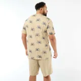 Remera de manga corta y cuello redondo en color beige con estampado integral de palmeras en tono azul oscuro.