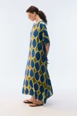 Kaftan maxi amplio de color amarillo, con escote redondo, mangas cortas y ruedo irregular. Presenta un diseño estampado a cuadros con efecto teñido.