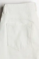 Bermuda de cinco bolsillos en denim de algodón rígido, corte baggy con cierre de botón y bajo deshilachado.