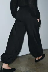 Pantalón negro de tiro medio con cintura ajustable mediante cordones y bajo abullonado con puño elástico.