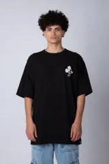Remera negra de corte oversize confeccionada en algodón pesado, con estampa pequeña de Mickey Mouse en el pecho y diseño gráfico en la espalda.