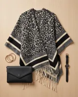 Poncho abierto con estampado animal print tipo leopardo en tonos grises y negros, con bandas horizontales en los bordes y flecos colgantes en el ruedo.