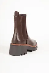 Bota marrón de cuero sintético, estilo Chelsea, con punta redonda, pieza elastizada en los laterales y suela tipo tractor de 6cm de alto.