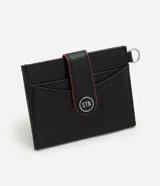 Billetera compacta de poliuretano color negro, con solapa frontal con detalles en rojo, botón a presión metálico con logo, compartimentos para tarjetas y argolla lateral.