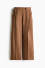 Pantalón sastrero de corte holgado color marrón, con pretina prolongada, cierre frontal y pinzas en las perneras amplias.