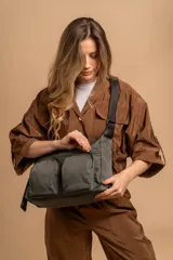 Bandolera de tafeta impermeable color beige, con dos bolsillos frontales con cierre y correa regulable. Diseño práctico y liviano ideal para uso diario.