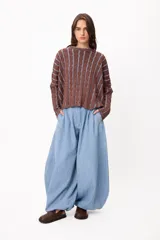 Pantalón de denim estilo palazzo con silueta holgada y diseño de pinzas en la cintura. Presenta un corte amplio y fluido, con cierre frontal y bolsillos laterales.