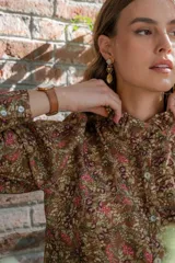 Camisa negra con estampado de flores y palmeras en tonos beige y rojo.