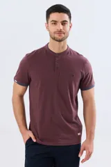 Remera estilo polo con cuello mao y manga corta, de color bordó con detalles en azul en los bordes de las mangas y cuello. Cuenta con cierre frontal parcial de tres botones y pequeño logo bordado en el pecho.