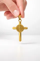 Dije de acero inoxidable con acabado dorado, que presenta una cruz con una medalla de San Benito integrada en el centro.