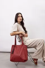 Bolso tipo shopper color rojo, confeccionado en 100% cuero vacuno, con diseño geométrico de paneles y detalle de fleco decorativo colgante.