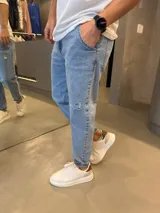 Jean de corte slouchy en color azul claro, con efecto desgastado y detalle de rotura en la rodilla. Presenta cintura con elástico y cordón ajustable, y terminación en puño elástico.
