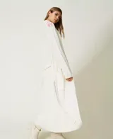 Maxi cárdigan tejido color crema con bordados florales y cinturón.