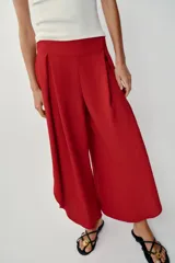 Pantalón fluido de tiro alto en color blanco, con pinzas delanteras, cintura elástica en la espalda y perneras anchas con aberturas laterales pronunciadas.