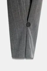 Pantalón de tiro alto con diseño de rayas verticales, corte recto y holgado. Presenta pliegues frontales, bolsillos laterales y bajo ajustable con botón.