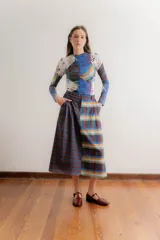 Falda midi de corte recto confeccionada en popelina de algodón, con diseño estampado floral en tonos azules y rojizos sobre fondo azul oscuro. Presenta un diseño con pinzas en la cintura y cierre frontal.