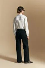 Pantalón de denim azul oscuro, de corte recto y tiro alto, con bolsillos delanteros aplicados y detalle de costura visible.