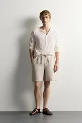 Bermuda de lino negro de corte relaxed fit, con cintura elástica ajustable mediante cordón y bolsillos frontales.