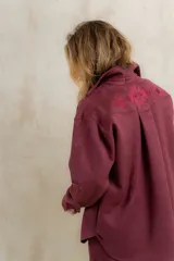 Camisa estilo western confeccionada en gamuza sintética color bordó, con diseño holgado y bordado geométrico en la parte superior de la espalda.