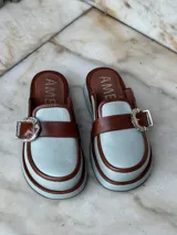 Suecos de cuero color celeste con detalles en marrón y hebilla plateada. Tienen un tacón de 3 cm.