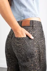 Pantalón de jean con estampado animal print en tonos oscuros, de corte recto y tiro medio. Cuenta con bolsillos traseros y etiqueta de cuero sintético con el logo de la marca en la cintura.
