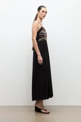 Maxi vestido largo de color negro, de corte recto y tirantes finos. Presenta un diseño bordado multicolor en la zona del pecho con motivos geométricos y florales.