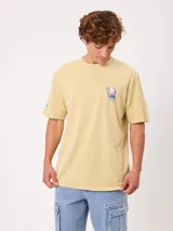 Remera Rusty de corte holgado, color amarillo, con estampa en la espalda de un personaje surfeando sobre un pez y textos descriptivos.