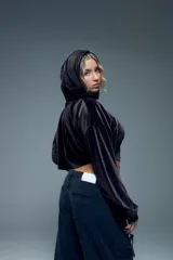 Canguro corto negro de terciopelo con capucha, mangas largas abullonadas con puños elastizados y abertura en el pecho.