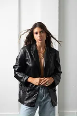Blazer de cuero sintético negro con solapas clásicas, cierre frontal con botones y corte recto.