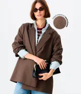 Blazer de corte sastrero y largo extendido, con estampado de cuadros tipo príncipe de gales en tonos marrones. Presenta cuello con solapa, cierre frontal con botones y mangas largas.