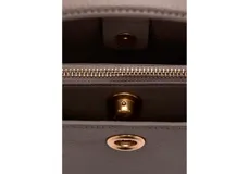 Bolso tipo bandolera y bolso de mano color marrón topo, con detalle de herraje metálico circular dorado en el centro y asa corta superior.