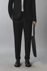 Pantalón de traje slim fit color negro, confeccionado en tejido con viscosa, con bolsillos frontales, bolsillos traseros de doble vivo y raya marcada en las piernas. Cuenta con cierre frontal con cremallera y botón.