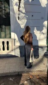 Pantalón de denim oscuro con corte recto y tiro medio. Presenta bolsillos traseros, cierre lateral invisible y tiras ajustables en la cintura.