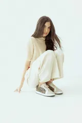 Championes de cuero color blanco con detalle de corona en animal print y talón verde. Cuentan con suela de caucho, lengüeta de gamuza y forro textil, con cierre mediante cordones al tono.