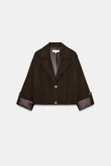 Blazer corto de color marrón oscuro, con cuello solapa, cierre frontal de botones y mangas largas con puños vueltos. Presenta un diseño con bajo elástico que le otorga una silueta ajustada en la cintura.