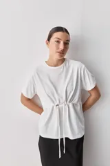 Remera de algodón blanca de manga corta y cuello redondo, con cordón ajustable en la cintura.