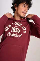 Hoodie bordó con capucha y cordones ajustables, presenta un estampado frontal con texto en color crema y bolsillo tipo canguro.