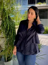 Camisa azul marino de manga larga con cuello camisero y cierre de botones. Presenta volantes horizontales en la parte delantera.