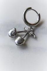 Aros de acero quirúrgico hipoalergénico, con argolla pequeña y dije colgante en forma de cerezas.