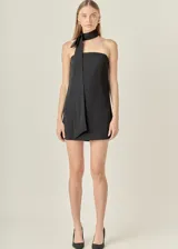 Vestido corto negro sin mangas con cuello choker y corbatín.