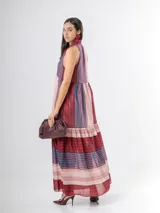 Vestido largo de corte halter en organdí, con estampado de rayas verticales y horizontales en tonos bordó, azul y crudo. Cuenta con un lazo en el cuello y un volado en la parte inferior.