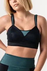 Bralette deportivo reductor negro con breteles anchos magenta regulables y escote alto. Confeccionado en jersey y tela de faja de alta contención.