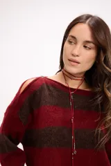 Buzo de tejido de punto con diseño de rayas horizontales anchas en color amarillo y marrón. Presenta cuello redondo, corte holgado y detalle de aberturas en los hombros.