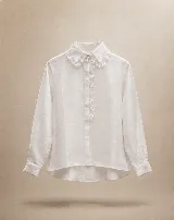 Camisa blanca de lino con cuello tipo Peter Pan amplio adornado con puntilla bordada, cierre frontal oculto y mangas largas con puños rectos.