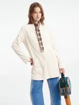 Chaqueta color crema de pana con cuello mao, cierre con botones y bolsillos frontales.