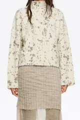 Jersey corto de corte boxy confeccionado en mezcla de lana, con cuello alto y mangas largas rectas, de color beige con diseño estampado tipo efecto salpicado en tonos gris y marrón.